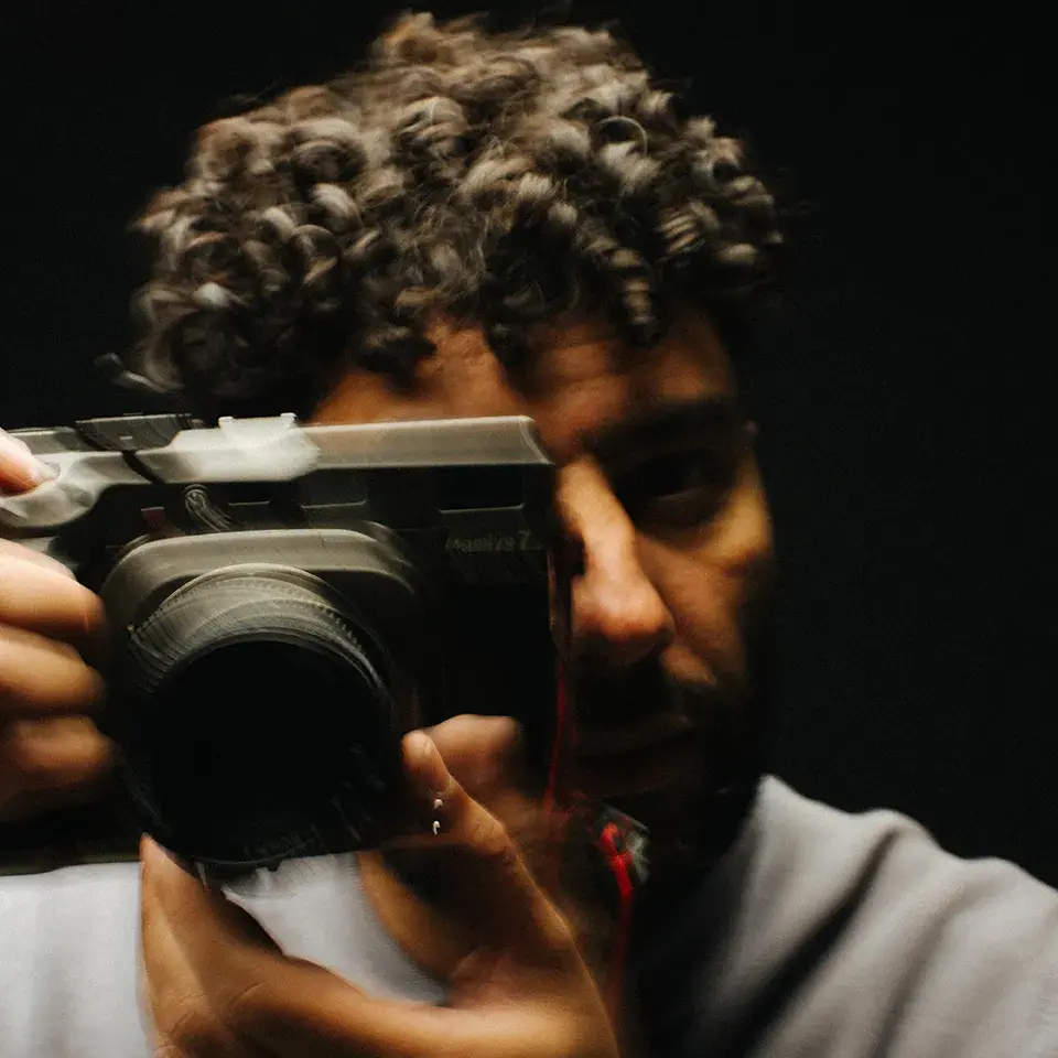 Man die door zijn spiegelreflex camera kijkt, &copy; Jari Nuno