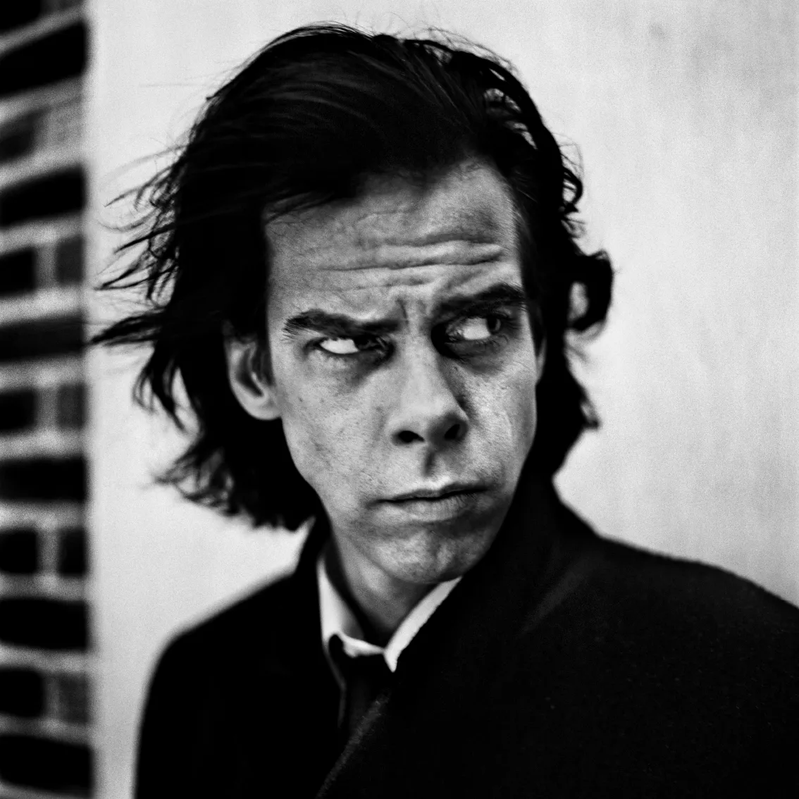 Een zwart-wit foto van het gezicht van Nick Cave voor de hoes van zijn nieuwe album in 1996 gefotografeerd door Anton Corbijn